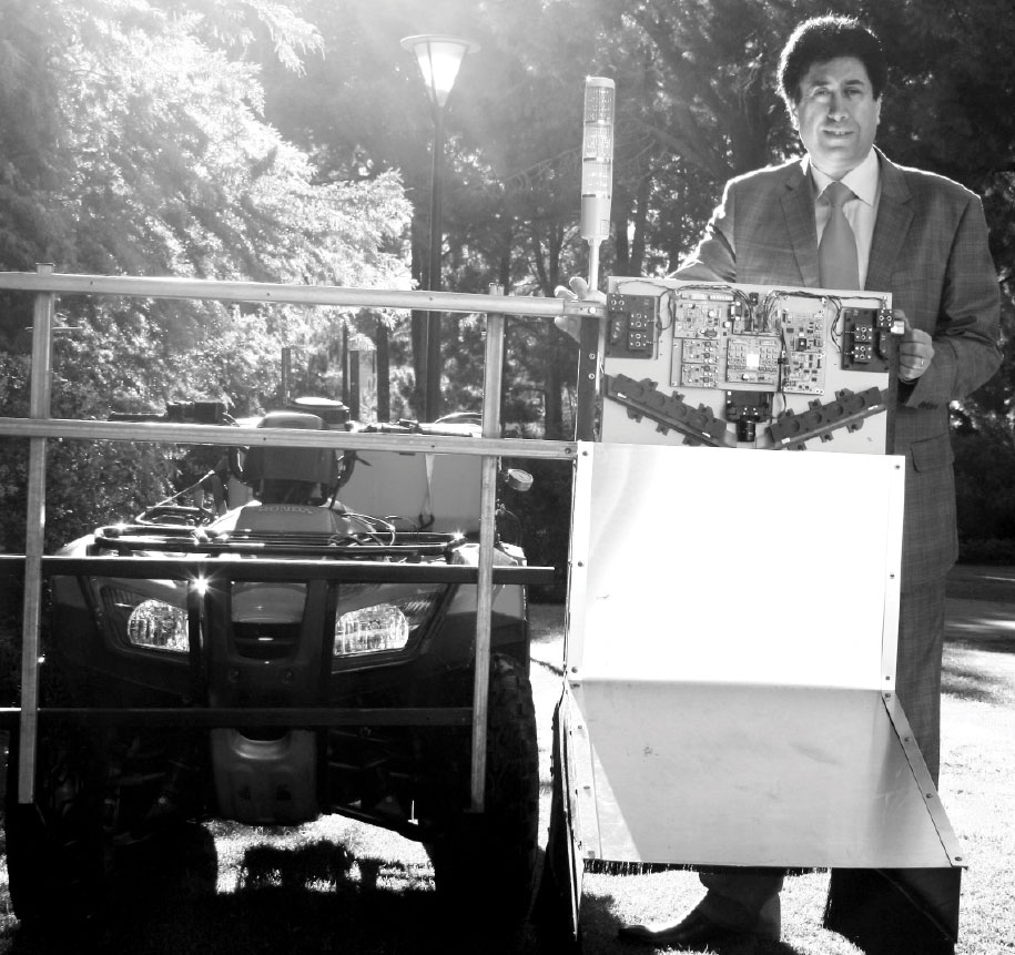 Black and white photograph of Professor Kamal Alameh with a piece of equipment – the spectral laser-based weed sensor.