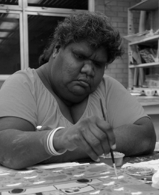 Black and white photograph of Lindy Brodie, a renowned Barkly artist. Lindy Brodie is painting the Creative Barkly logo.