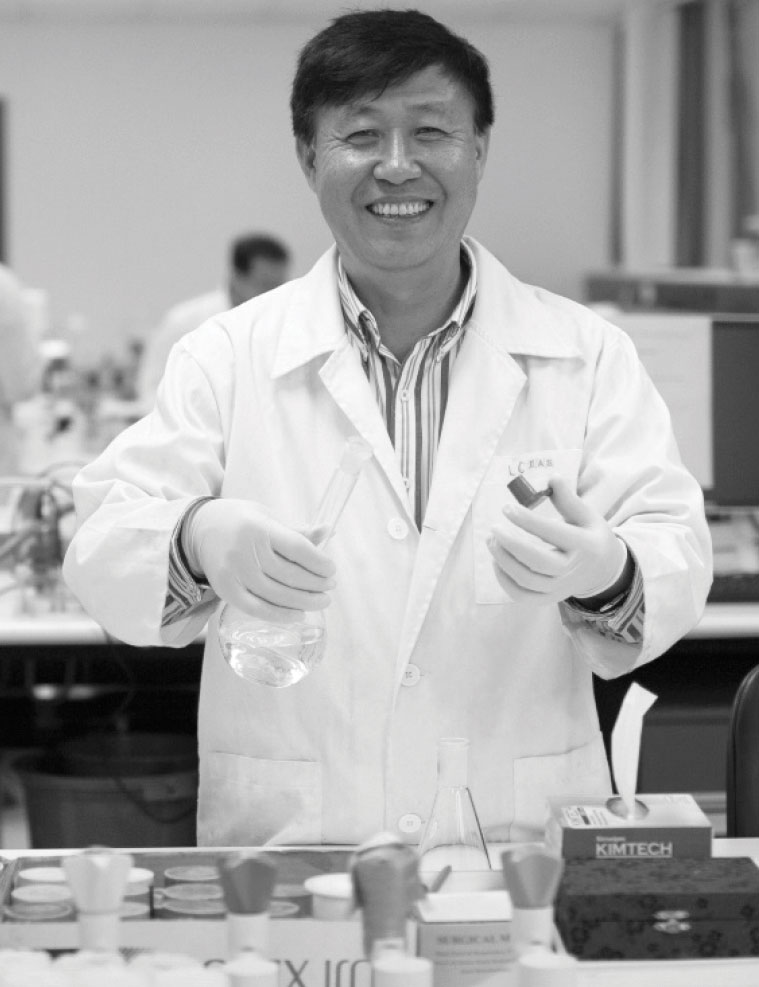 Black and white photograph of Professor Huijun Zhao holding laboratory equipment.