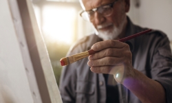 older man painting on canvas