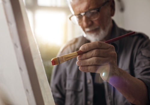 older man painting on canvas