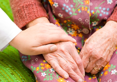 Young hand holding older woman's hand